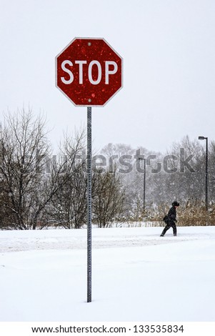 stop sign with a winter walk during a snowstorm