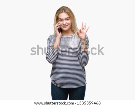 Young caucasian woman showing smartphone screen over isolated background doing ok sign with fingers, excellent symbol
