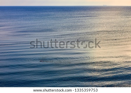 Idyllic seascape with soft morning color. The calm sea reflects the clear sky like a mirror. Blue sea background with rising sun