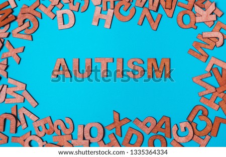 The word Autism from wooden letters on a blue background. The problem is in socialization, communication