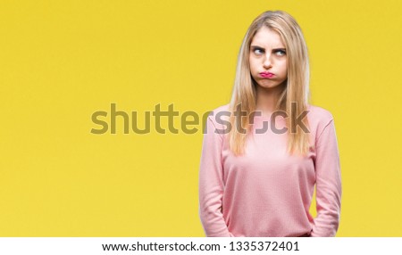 Young beautiful blonde woman wearing pink winter sweater over isolated background making fish face with lips, crazy and comical gesture. Funny expression.