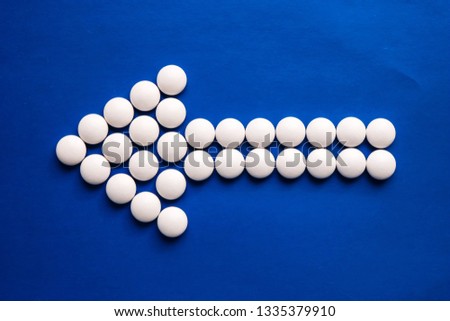 Arrow of white pills on blue background. Medicine concept.