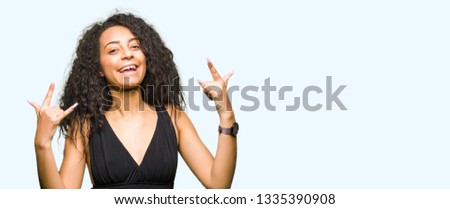 Young beautiful girl with curly hair wearing fashion skirt shouting with crazy expression doing rock symbol with hands up. Music star. Heavy concept.