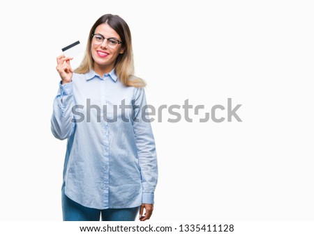 Young beautiful business woman holding credit card over isolated background with a happy face standing and smiling with a confident smile showing teeth