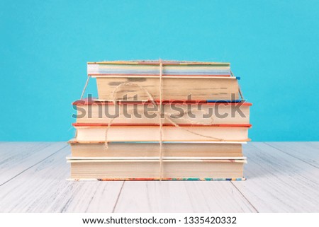Stack of books and pink heart. Books with jute ribbon bow as gift on blue background. Education background with copy space, back to school concept.