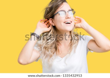 Beautiful young blonde woman wearing glasses over isolated background Smiling pulling ears with fingers, funny gesture. Audition problem
