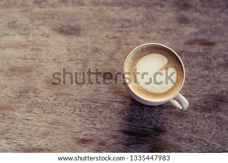 why cup of coffee on a light wooden table, top view milk heart patterned heart