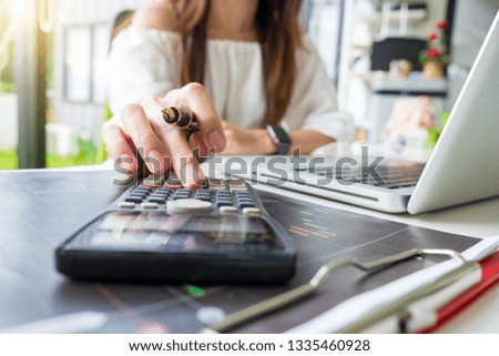 business hand working with finances about cost and calculator and laptop with tablet on withe desk at office warm colours sun light
