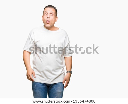 Middle age arab man wearig white t-shirt over isolated background making fish face with lips, crazy and comical gesture. Funny expression.