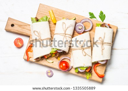 Burritos tortilla wraps with beef and vegetables on white wooden background.  Mexican cuisine, latin american food. Top view.