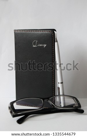 Eye glasses, blank notepad, and pen on the table