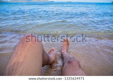 Man is on beach and feet in the sea 