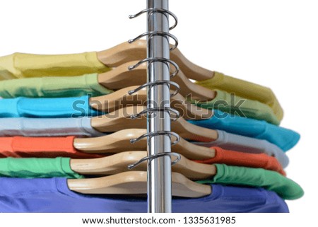 T-shirts of different colors hang on closing rack on wooden hangers are isolated on white background. View from above.