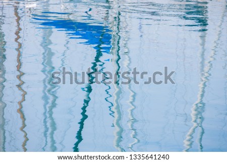 Reflection of white masts from yachts and ships in the sea and water