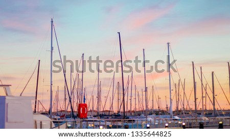 Scenic picture of the silhouettes of yacht masts against the blue and pink sunset sky on the Mediterranean coast in the port of the Spanish city