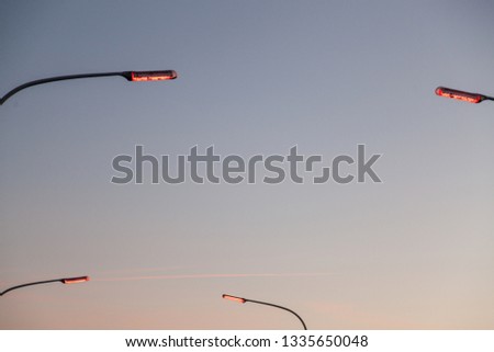 The end of four street lamps glowing red on a background of a purple and blue evening sky, minimalist abstract shot