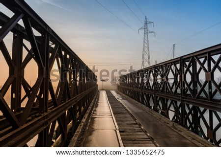 iron bridge at dawn with high voltage pylon in the background