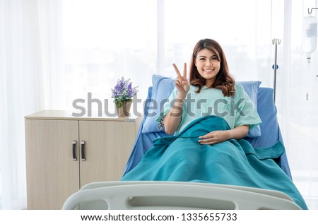 Portrait of happy female patient in hospital room with cheerful posture. The sick inpatient smiling to her doctor and nurse as she recovering and worry free. Insurance concept. Copy space provided. 
