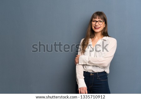 Woman with glasses over blue wall With happy expression