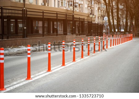 A row of red and yellow plastic barrier on the road for cars moving across the dividing strip. Barrier which prevent the exit of the vehicle from line and for cars not to park on roadway