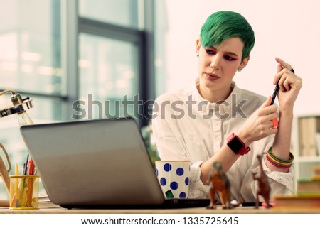 Interesting idea. Pleasant thoughtful woman looking at the laptop screen while thinking about a new idea