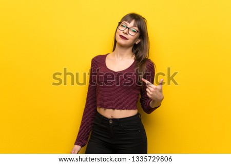 Woman with glasses over yellow wall proud and self-satisfied