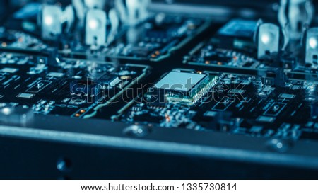 Close-up Macro Shot of Electronic Factory Machine at Work: Printed Circuit Board (PCB) Being Assembled with Automated Robotic Arm, Surface Mounted Technology (SMT) Connecting Microchips to Motherboard Royalty-Free Stock Photo #1335730814