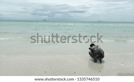 The man is sitting and taking a photo at the sea