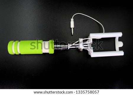an extensible selfie stick with an adjustable clamp on the end on a black background