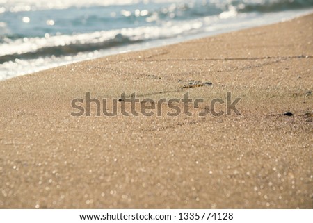 Sand coastline beach view with blurred waves on background. Close up sand. Copy space. Travel photography concept.