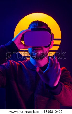 VR videogame experience in 80's synthwave and retrowave futuristic aesthetics. Man wearing virtual reality goggles wireless headset and interacting with hand gestures. 