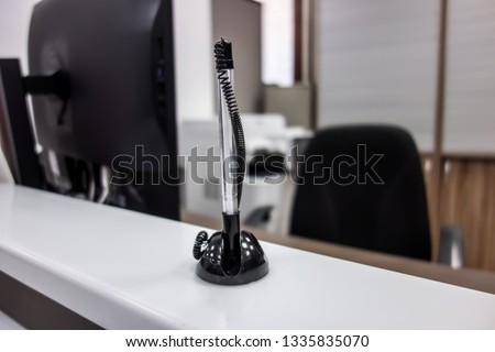 The black pen attached to the reception Desk on the background of the office.