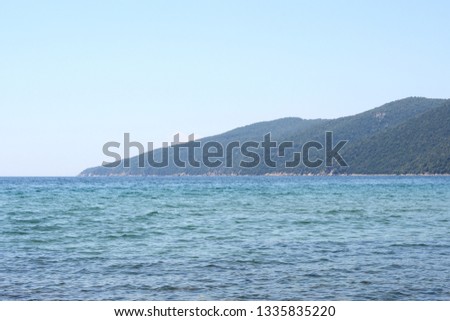 Beautiful minimalistic seascape of calm sea, sandy beach, blue sky, Greece. Horizontal.