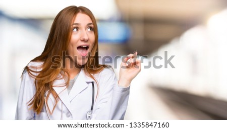 Redhead doctor woman intending to realizes the solution while lifting a finger up in the hospital