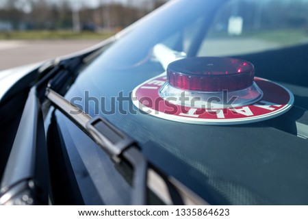 German police signaling disk behind the windscreen of a civilian police car (translation: stop police)