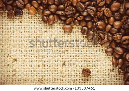 Coffee beans scattered on burlap can be used as background. Toned picture