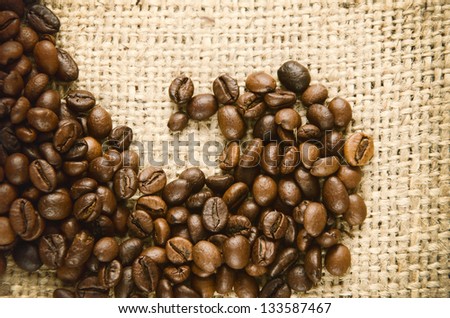 Coffee beans scattered on burlap can be used as background. Toned picture