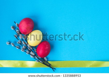 Easter background with colorful eggs, a willow branch and a yellow ribbon. Place for text