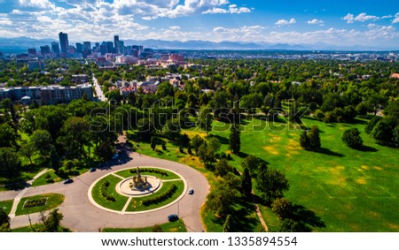 vast City park green spaces circle pattern monument aerial drone view high above Denver , Colorado Downtown skyline in background with Rocky Mountains