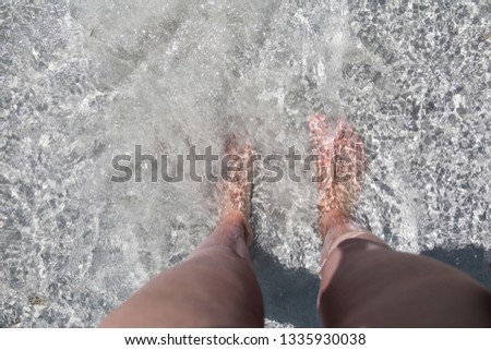  Picture of young woman's legs standing in a clear bright water with a white sand. Enjoying the water.