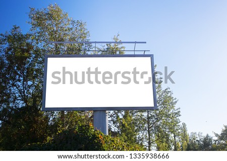 Blank billboard in a green scenery with a bright blue sky