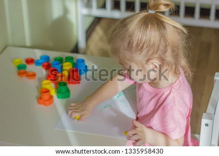 little girl drowing with paints prints and stamps colors.