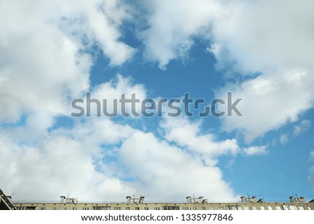 Blue sky with big clouds and the roof of the house