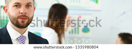 Young handsome teacher man in suit with workgroup seminar board with chart coaching background. Lecturer for applicants retraining financial statistics management enterprise etiquette corporate spirit