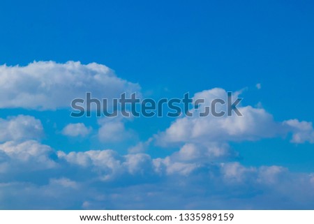 Colour photograph of blue sky and white clouds. Natural background image illustrating good weather, open space, freedom, calm and peaceful environment.