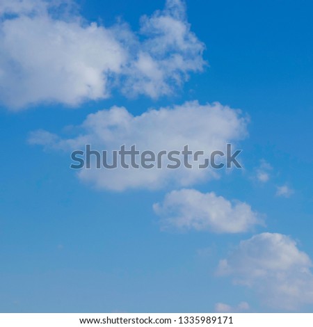 Colour photograph of blue sky and white clouds. Natural background image illustrating good weather, open space, freedom, calm and peaceful environment.