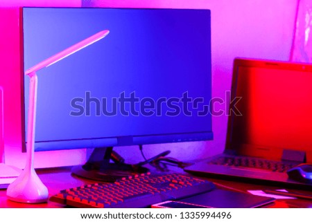 Workplace digital designer. Freelancer workplace in neon light. Computer, graphics tablet and smartphone on the table. Place for creativity in blue-pink light