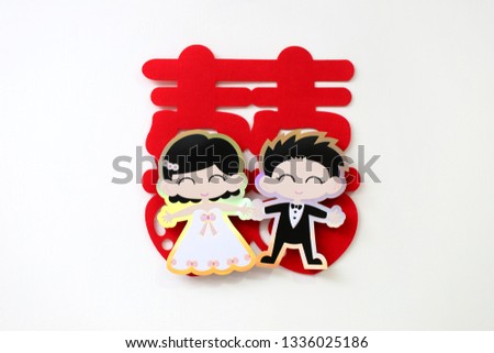 Cute Chinese wedding symbol paper cut with groom and bride cartoon stick on the wall of bride's room. Chinese Wedding with "Double Happiness" Text Calligraphy Illustration on paper cut design.