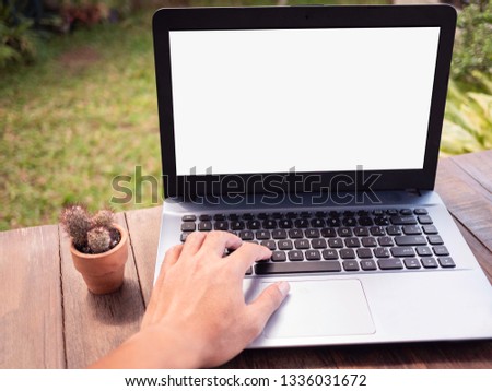 Close up hand of business Asian men; using computer laptop on wooden table with cactus planted in small pots over nature background at the backyard. Happy on weekend concept.