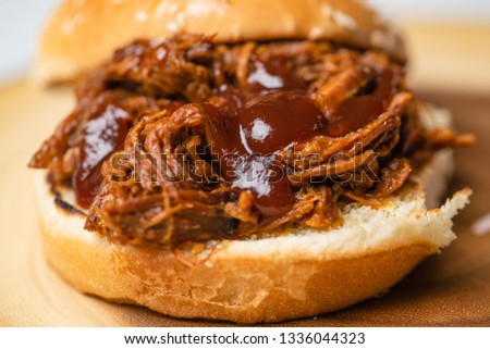 Close up of a barbecue pulled pork sandwich made out of pork belly. slow cooked for over 18 hours. on a sesame bun  and extra bbq sauce
